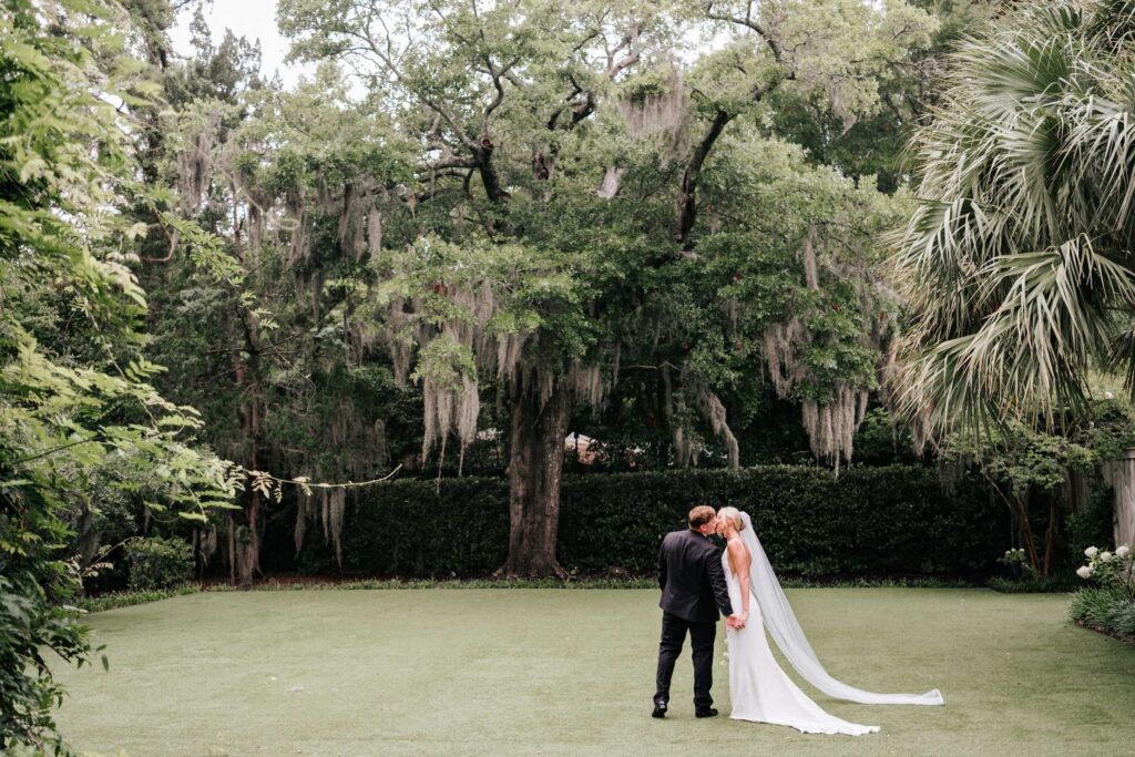 Couple enjoying a moment together in the yard of Wrightsville Manor with palm trees and spanish moss.