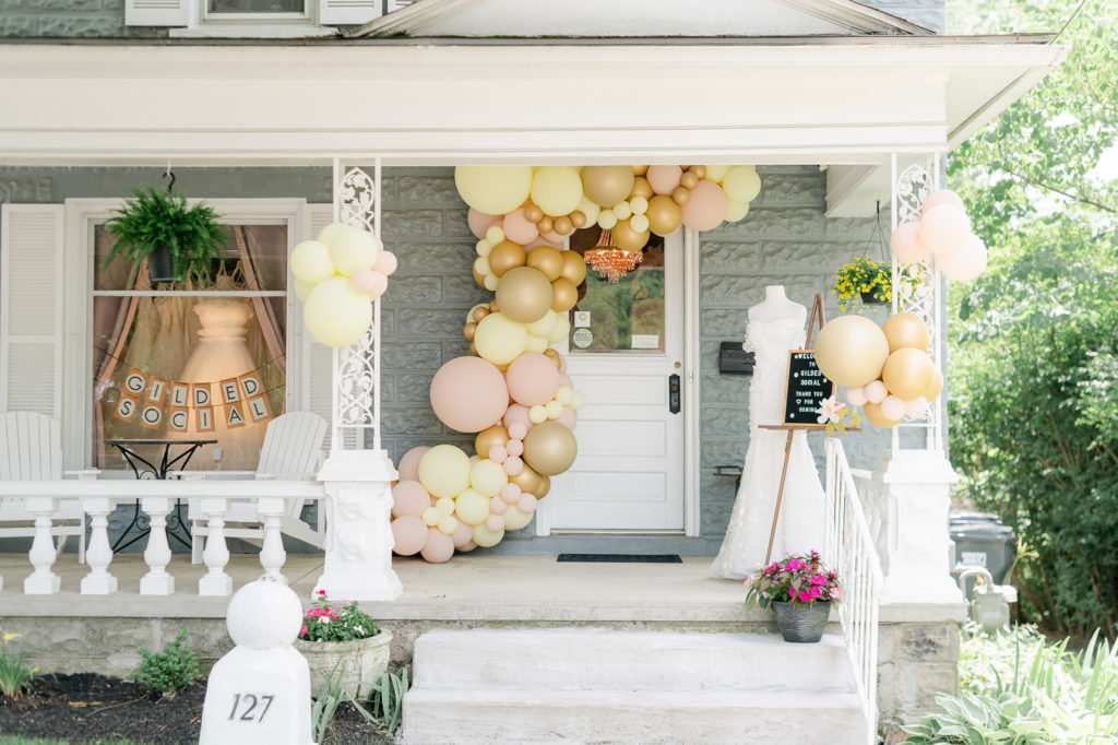 Exterior of Guilded Social showing a dress and some balloons. This is a Bridal shop in Columbus Ohio.