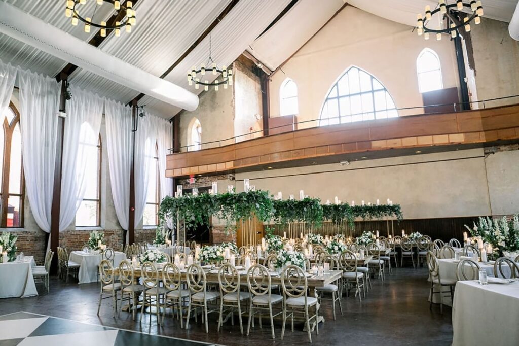 Brooklyn Arts Center with long tables adorned with lush green ivy centerpieces and candles. The table is dressed with table settings and florals.