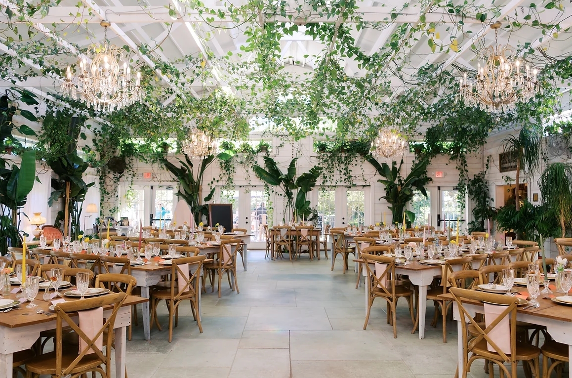 Carolina Home and Garden venue with rows of chairs and tables with ivy and pink flowers lining the ceiling.