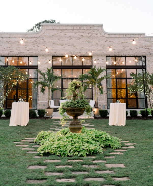 Wrightsville Manor Facade with Stone front with large paned windows ceiling to floor. Fountain and lush grass and greenery surrounds a table scape setting ready for a wedding.