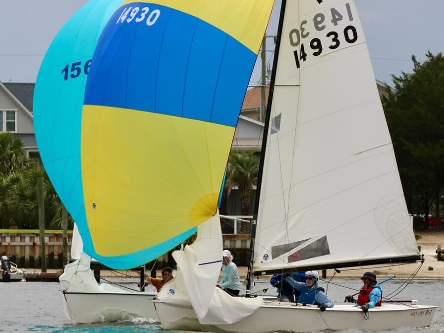 Carolina Yacht Club boats with yellow and blue sails on the water.
