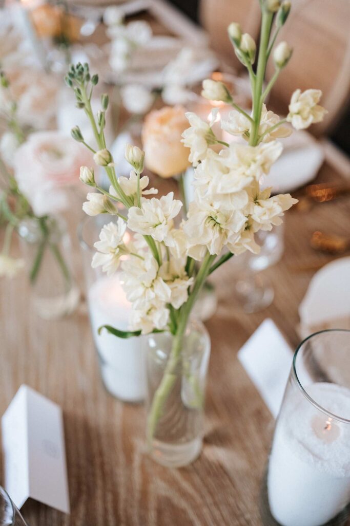 Wedding decor at the reception with flowers, candles, and a unique wooden table.